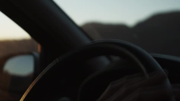 Detailní záběr mužské ruky držící volant při jízdě autem po silnici. Nízká světelná scéna v západu slunce — Stock video