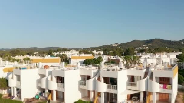 Luftaufnahme schöner traditioneller Häuser mit Fahrzeugen, die auf einer leeren Straße geparkt und von Bergen umgeben sind, an einem frühen Morgen auf Ibiza in Spanien — Stockvideo