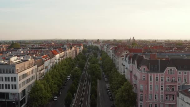 Forwards fly above wide street with railway tracks and trees in city. Morning shot of urban neighbourhood. Berlin, Germany — Stock Video