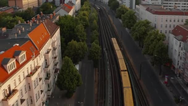 Утренний вид с воздуха на два проходящих мимо поезда. Вперед, летим над широкой улицей с линиями Сбан. Берлин, Германия — стоковое видео
