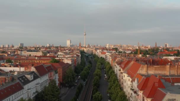 Vista aérea de la ciudad de la mañana iluminada por el sol brillante. Volar por encima de la calle ancha con vías férreas hacia Fernsehturm torre de televisión. Berlín, Alemania — Vídeo de stock