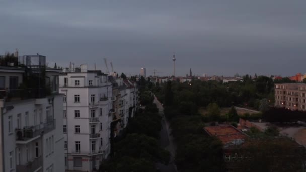 Forwards fly above public park in urban neighbourhood in morning before sunrise. Fernsehturm TV tower in distance. Berlin, Germany — Stock Video