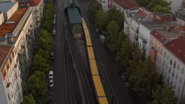Vista aérea del tren que conduce en la calle de la ciudad. Seguimiento hacia adelante de la unidad amarilla Sbahn. Edificios iluminados por el sol de la mañana. Berlín, Alemania — Vídeo de stock