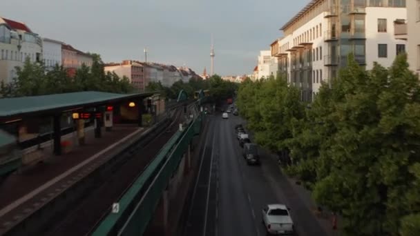 Framåt spårning av stadståg som kör på förhöjd järnväg i Schoenhauser Allee Street. Upphöjda bilder avslöjar stadsbilden upplyst av starkt morgonsol. Berlin, Tyskland — Stockvideo