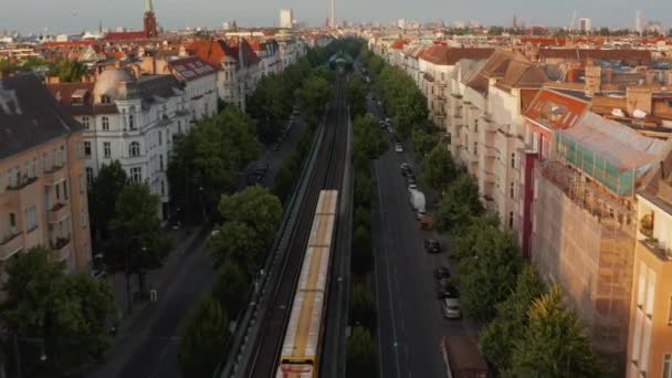 Inoltra il monitoraggio del treno scansione guida in un'ampia strada sulla grande città. Tetti di edifici illuminati dal sole mattutino. Vola verso la torre TV Fernsehturm. Berlino, Germania — Video Stock