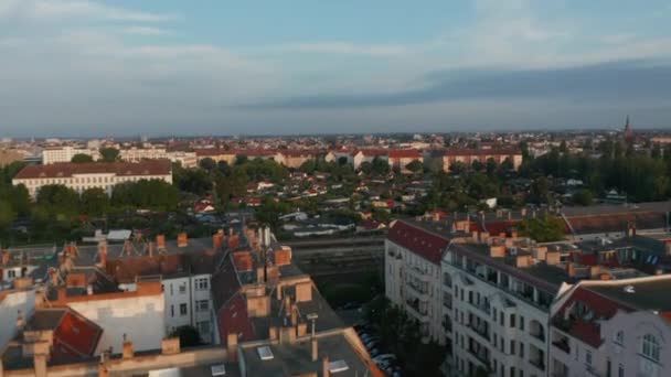 Forwards fly above urban neighbourhood. Aerial view of train driving on railway track. Scene lit by bright morning sunshine. Berlin, Germany — Stock Video