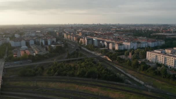 Luchtfoto panning uitzicht op spoorwegknooppunt en residentiële wijk in grote stad. Schoot tegen de felle ochtendzon. Berlijn, Duitsland — Stockvideo
