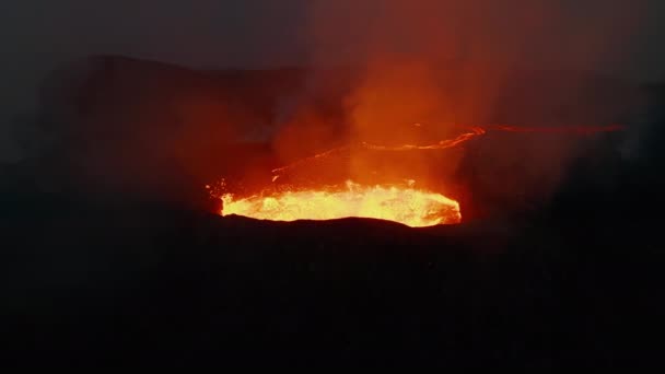 Извержение вулканического кратера. Крупный план кипящего магматического материала в кратере и потока лавы на заднем плане. Вулкан Фаградальсфьол. Исландия, 2021 — стоковое видео