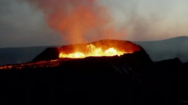 Erimiş magma patlaması sırasında volkan kraterinin etrafında uçmak. Sıcak lav akıntısı aşağı akıyor. Fagradalsfall volkanı. İzlanda, 2021