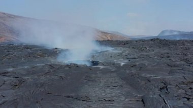 Yeni lav alanındaki soğutucu lav tabakasının içindeki delikten çıkan duman görüntülerini kaydır. Fagradalsfall volkanı. İzlanda, 2021