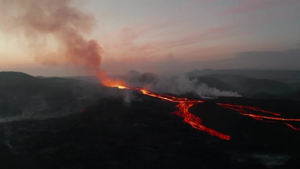 Kraan beelden neer van uitbarstende vulkaan tegen roze dageraad lucht. Hete gesmolten lava tekent oranje lijnen op helling. Fagradalsfjall vulkaan. IJsland, 2021 — Stockvideo