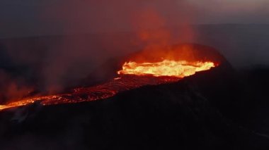 Kraterden çıkan kaynamış magmatik madde. Parlayan lav dışarı çıkan gazları aydınlatıyor. Sıcak lav akışı. Fagradalsfall volkanı. İzlanda, 2021