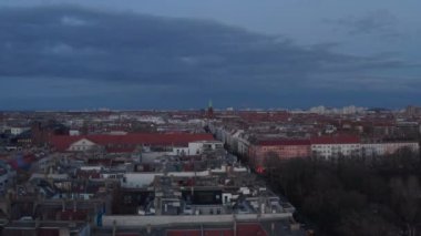 Berlin, Almanya 'da bulutlu bir sabahta, sokağın karşısındaki ağaçlarla çevrili geleneksel tuğlalı evlerin çatılarını çekiyorlar.
