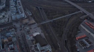 Berlin, Almanya 'da sabahın erken saatlerinde parkedilmiş konut evleri ve araçların yakınındaki köprüde yürüyen insanların hava yavaş çekim görüntüsü.