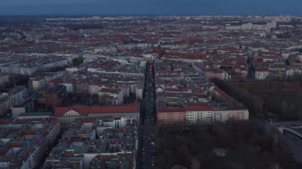 Établissez un plan au ralenti du toit traditionnel d'une maison en brique en face de la rue et de la ruelle entourée d'arbres avec des véhicules stationnés et en mouvement tôt le matin à Berlin, en Allemagne — Video