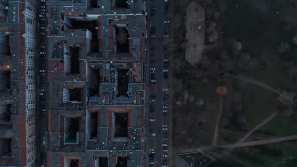 Blick von oben auf das Dach eines Wohnhauses mit geparkten Fahrzeugen, die sich morgens in Berlin über eine von Bäumen umgebene Straße bewegen — Stockvideo