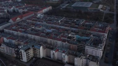 Berlin, Almanya 'da bulutlu bir sabahın erken saatlerinde ağaçlarla çevrili geleneksel tuğlalı ev ve caddenin karşısındaki binanın hava yavaş çekim görüntüsü.