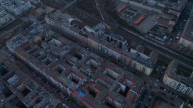 Berlin, Almanya 'da sabahın erken saatlerinde ağaçlarla çevrili, park halindeki ve caddelerde ilerleyen araçları olan boş ev çatılarının yavaş çekim görüntüsü.