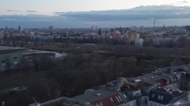 Berlin, Almanya 'da bulutlu bir sabahta araçları park etmiş ve binanın dışında hareket eden boş konut evlerinin hava dairesel hareketi hızlı bir şekilde görülüyor.