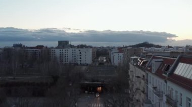 Berlin, Almanya 'da bulutlu bir sabahta, binalar ve ağaçlarla çevrili caddenin bir tarafında arabalarla yürüyen insanların ve araçların hava görüntüsü