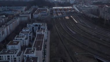 Berlin, Almanya 'da ağaçların yanından geçen bir yolcu treninin hava görüntüsü sabahın erken saatlerinde konut eviyle çevrili.