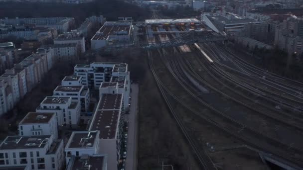 Vista aérea de un tren de pasajeros que pasa por los árboles en Berlín, Alemania, rodeado de casa residencial durante una madrugada — Vídeo de stock