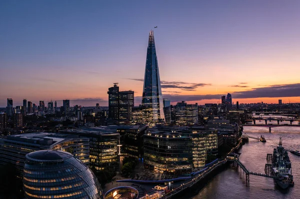 Güzel Londra şehrinde küçük binalarla çevrili bir finans kulesinin hava manzarası mavi gökyüzü ile bulutlu bir günbatımı akşamında