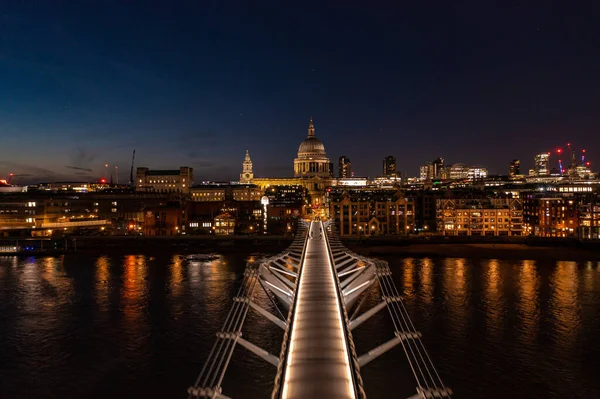 Londra 'daki Millennium Köprüsü' nün hava görüntüsü. Işıklar ve insanlar geceleri kilise kubbesine doğru yürüyorlar.
