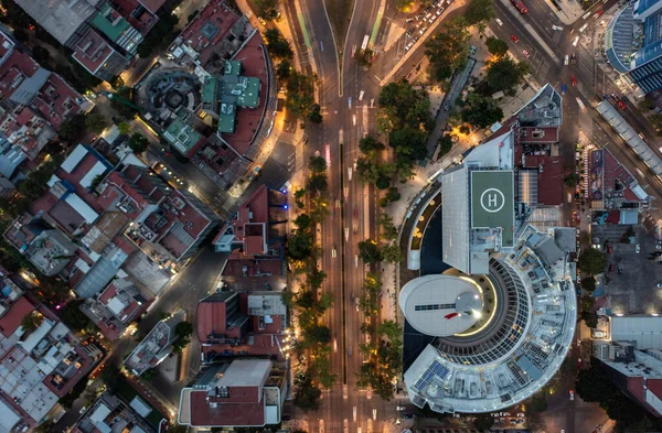 Πουλιά άποψη των αυτοκινήτων που τρέχουν στο δρόμο που περιβάλλεται από εμπορικό κτίριο με ελικοδρόμιο και κατοικίες στην Πόλη του Μεξικού το βράδυ — Φωτογραφία Αρχείου