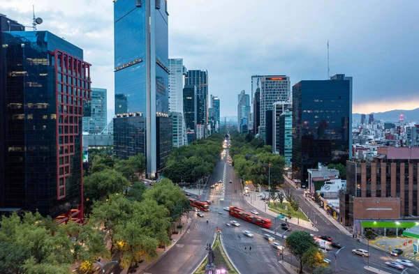 Mexico City 'de bulutlu mavi gökyüzünün altında gün boyunca hareket halindeki otobüs ve araba ile finansal gökdelenlerin hava manzarası