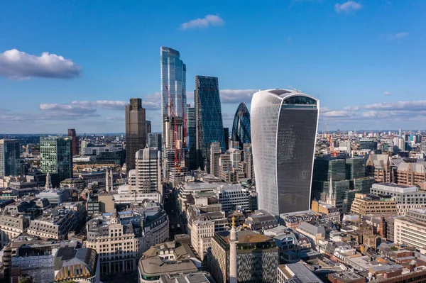 Mavi gökyüzü bulutlu bir günde Londra 'nın güzel şehrinde küçük binalarla çevrili bir finans kulesinin hava manzarası.