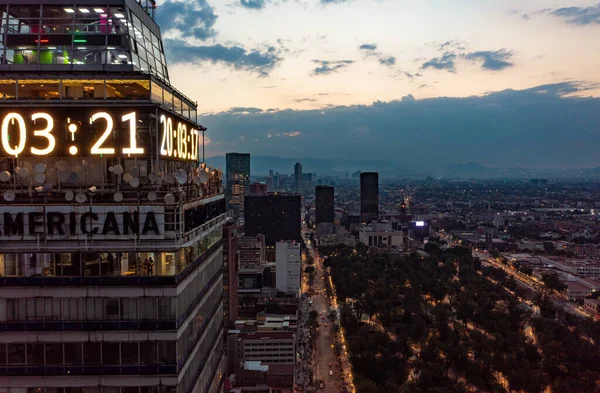 Flygfoto över finansiella skyskrapor visar tid på digital klocka i hörnet av byggnaden på natten i Mexico City under molnig himmel — Stockfoto