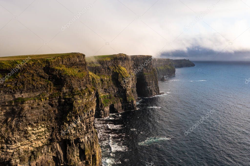 Beautiful and famous Irish cliffs of Moher in west coast of Ireland with calm and sea water under a cloudy white sky during day