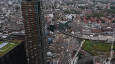 İleri, şehrin üzerinde uçar. Yol kavşağına eğil ve caddenin üzerindeki demiryolu köprüsüne. Yollarda giden araçlar. Londra, İngiltere