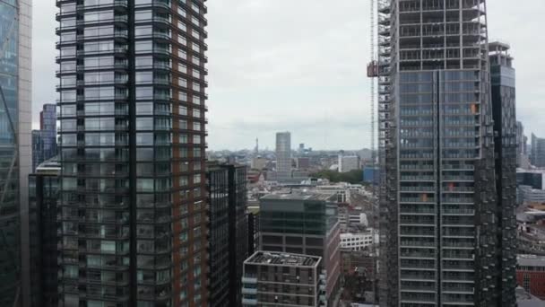 Images en descente sur de grands bâtiments modernes avec des façades en verre brillant reflétant le ciel. Immeubles de bureaux ou appartements en centre ville. Londres, Royaume-Uni — Video