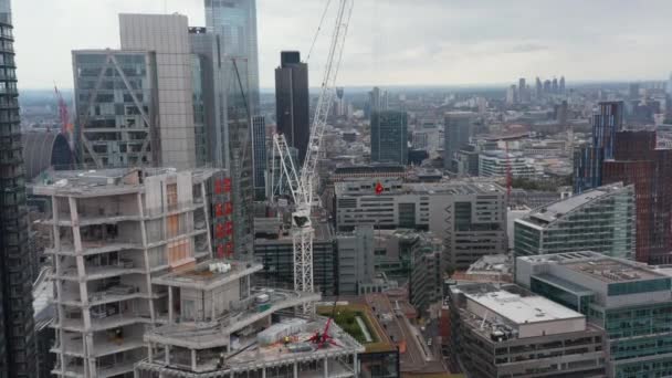 Filmagem ascendente de guindaste no novo local de constrição de arranha-céus. Edifícios altos da baixa à volta. Londres, Reino Unido — Vídeo de Stock