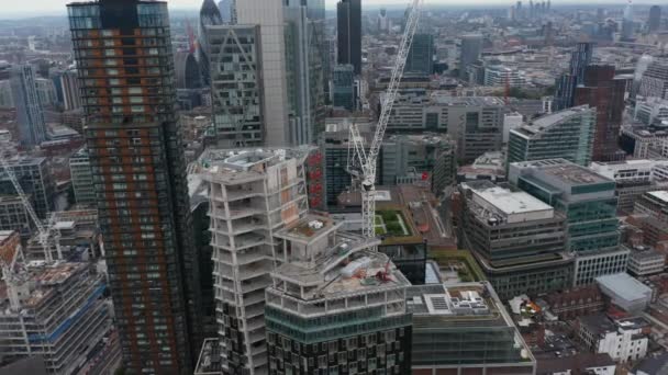 Slide and pan footage of tall building construction. Building of downtown skyscraper. Aerial view of properties in business centre. London, UK — Stock Video