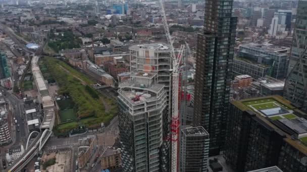 Fliegen Sie um die Baustelle eines neuen Wolkenkratzers im Shoreditch District. Aufgekipptes Stadtbild. London, Großbritannien — Stockvideo