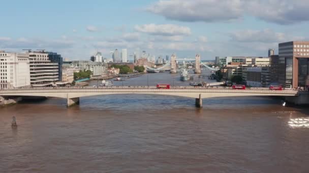 Adelante vuelan por encima de la superficie del río Támesis. Tres pisos dobles rojos conduciendo en el Puente de Londres. Histórico Puente de la Torre bien conocido en el fondo. Londres, Reino Unido — Vídeos de Stock