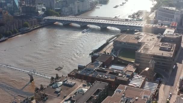 Høj vinkelvisning af bygninger på havnefronten ved Millennium footbridge over Themsen. Vip op afsløre for at dreje floden og moderne bygninger på sydbredden. Udsigt mod solskin. London, Det Forenede Kongerige – Stock-video