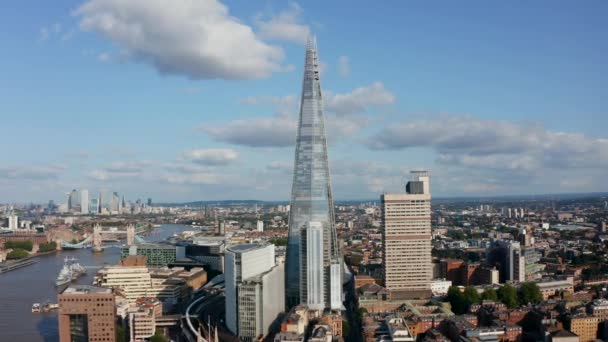 Vlieg rond de Shard wolkenkrabber. Modern futuristisch design hoog gebouw met conische vorm. Historische toren brug en hoge kantoorgebouwen in Canary Wharf op de achtergrond. Londen, Verenigd Koninkrijk — Stockvideo