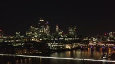 Thames nehrinin su yüzeyine iniş görüntüleri. City Finansal ve Millennium Köprüsü 'ndeki gökdelenlerin gece görüşü. Londra, İngiltere