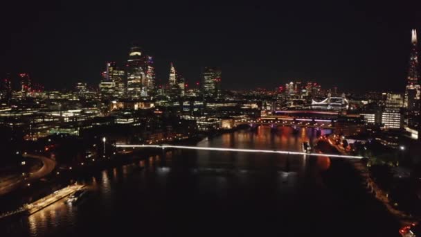 Aerial night view of large town lit by thousands of lights. Forwards fly towards group of skyscrapers in City financial district. London, UK — Stock Video