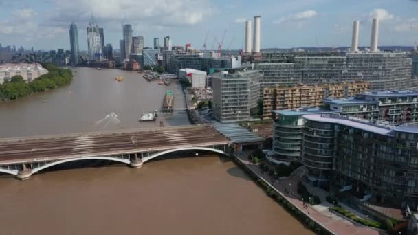 Hacia adelante vuelan hacia el puente ferroviario multipista. Modernos edificios de apartamentos en la orilla del río. Alto rascacielos modernos en el fondo. Londres, Reino Unido — Vídeos de Stock