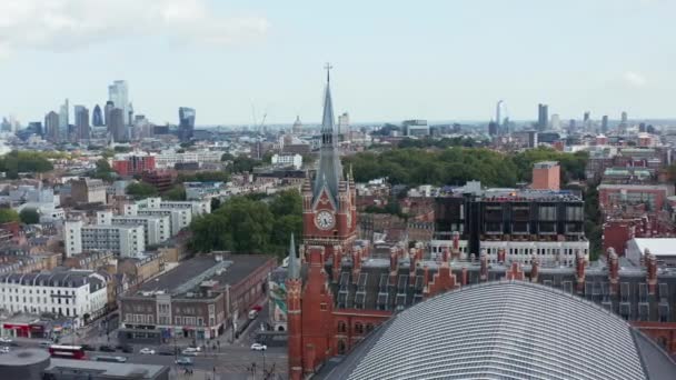 Widok z lotu ptaka z czerwoną ceglaną wieżą zegarową na pierwszym planie i nowoczesnymi wysokimi drapaczami chmur w tle. Londyn, Wielka Brytania — Wideo stockowe