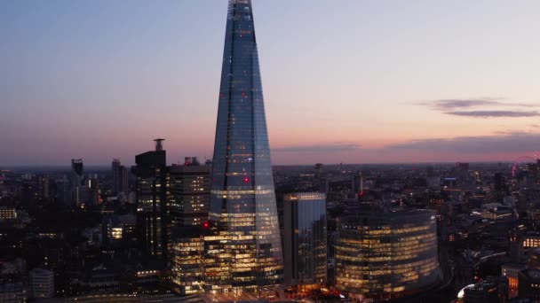 Alto moderno edificio cubierto de cristal brillante que se eleva por encima de los alrededores. Vista aérea elevada de la tarde contra el cielo crepuscular. Londres, Reino Unido — Vídeos de Stock