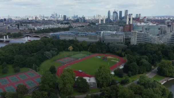Вид с воздуха на спортивный комплекс Баттерси Парк и современные жилые дома на Темзе. Высокие небоскребы на заднем плане. Лондон, Великобритания — стоковое видео