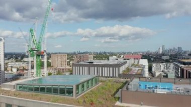 Şehirdeki modern apartmanların üzerinde alçaktan uçuyor. Yenilenebilir kaynaklardan enerji toplamak için ısıyı ve fotovoltaik güneş panellerini azaltacak yeşil çatı. Londra, İngiltere