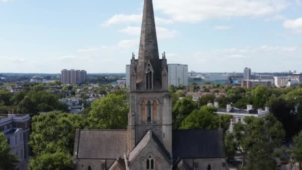 Forwards fly towards tower of gothic church. Closeup view of arches and decoration of spire. Historic building surrounded by trees in town. London, UK — Stock Video