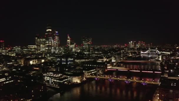 Night scene of large town. Modern tall buildings on City financial and economical centre. Backwards reveal of Thames river and its bridges. London, UK — Stock Video